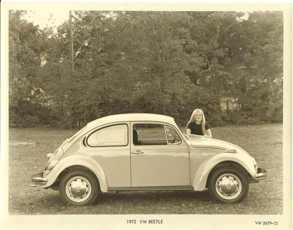1972 Volkswagen Beetle promo photo with person leaning on front fender in outdoor setting