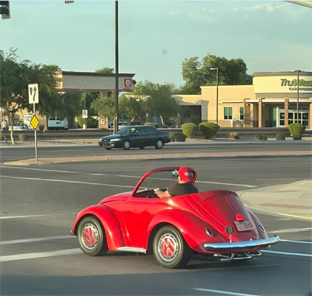 Red custom VW Beetle shorty convertible with shortened wheelbase being driven on a public road.