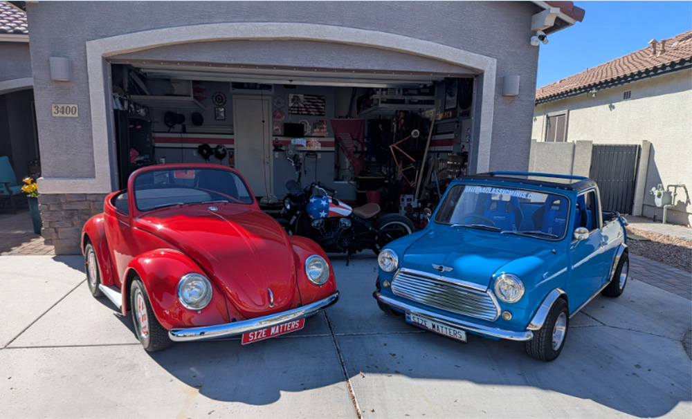 A custom red VW Beetle shorty convertible parked next to a classic blue Mini Cooper in a driveway in front of a garage, both cars displaying "SIZE MATTERS" front license plates.