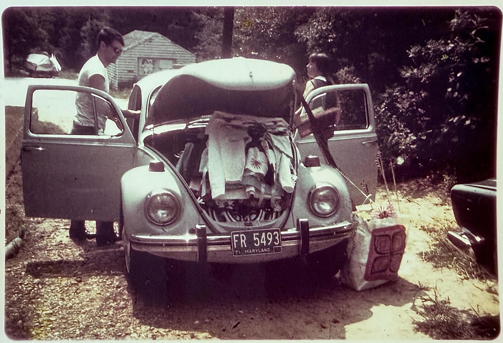 Vintage Volkswagen Beetle packed for a trip, Dave Cooks parents standing beside it in a rural setting