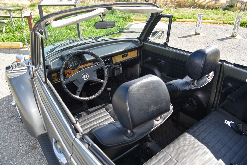 Interior of a 1979 Volkswagen Super Beetle convertible with black vinyl seats and wood-trim dashboard