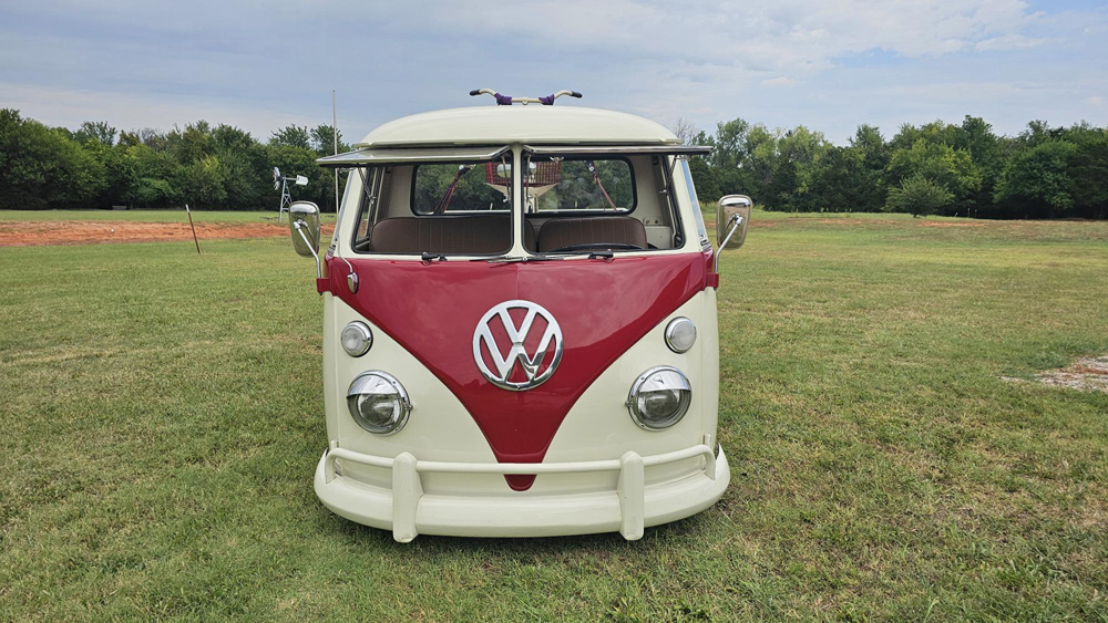 Front view of cream and red VW Type 2 with roof rack parked on grass