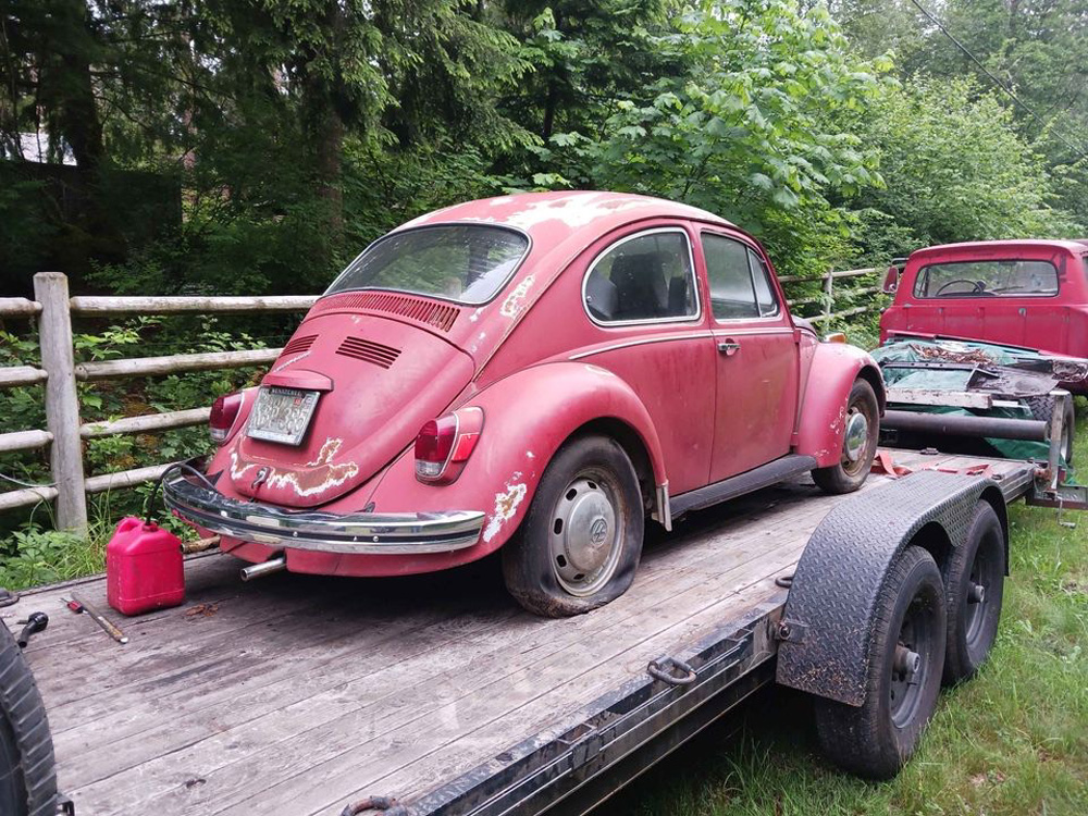 Red Beetle on a flatbed trailer showing rust and wear during transport