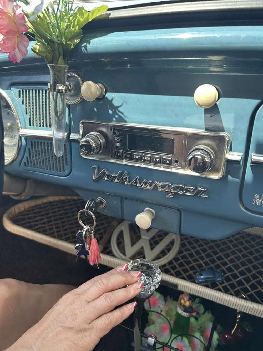 Close-up of vintage VW dashboard with chrome radio, Volkswagen script, and keys in ignition
