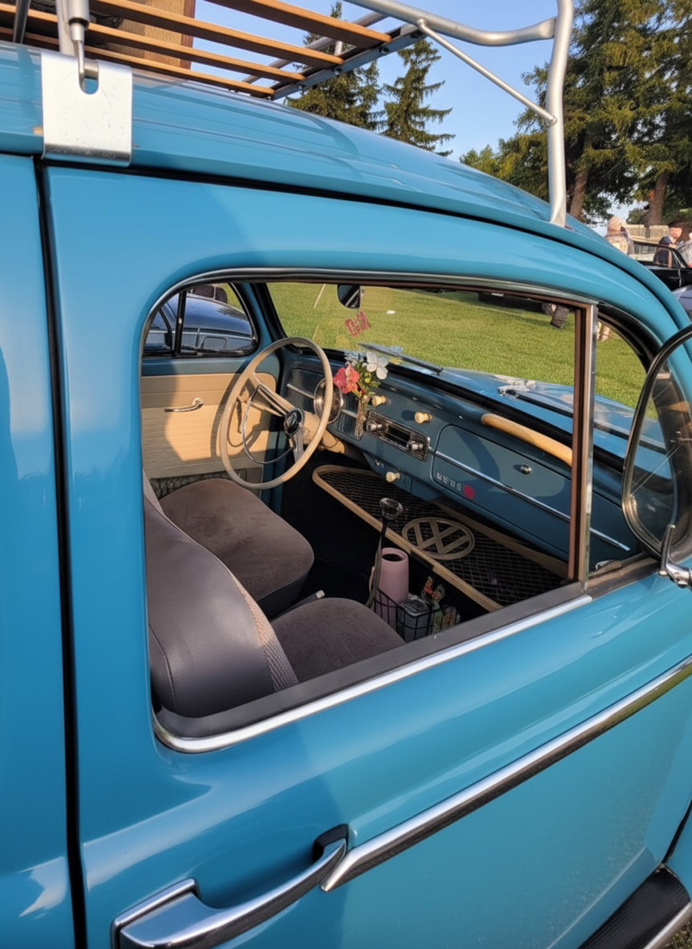 Interior of vintage VW Beetle showing beige steering wheel, dashboard, and floral dash decor