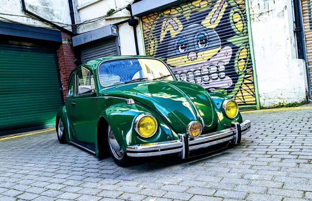 Green VW Bug parked by a mural