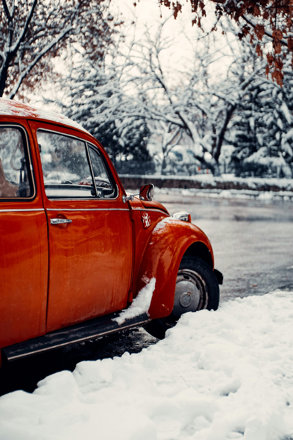 A close-up of a VW's narrow tires cutting clean, deep tracks through a thick layer of slush, illustrating how the thin profile slices down to the pavement for superior winter traction.