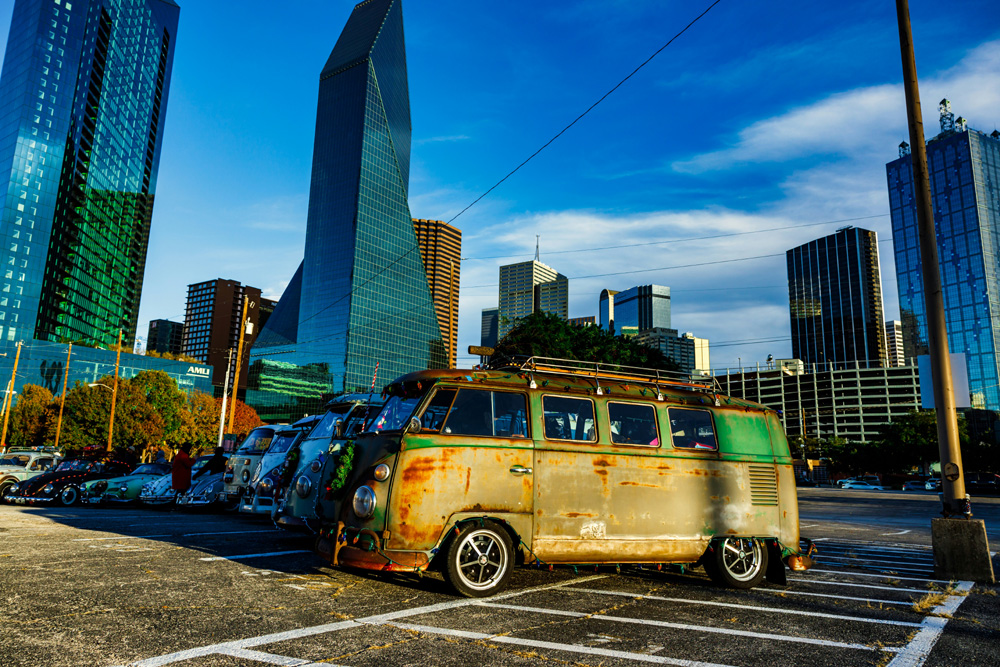 Row of vintage Volkswagen buses parked in front of a city skyline