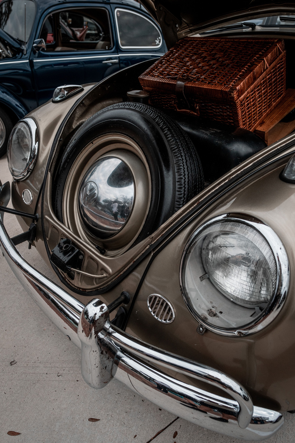 Volkswagen Beetle front trunk open showing spare tire and wicker picnic basket