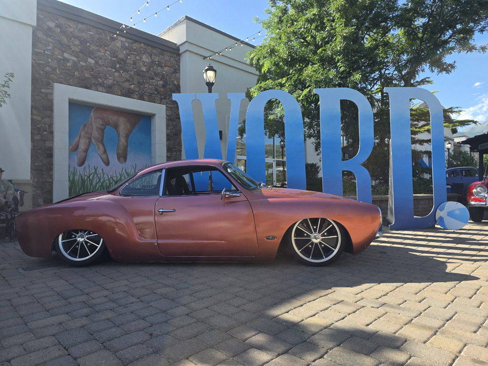Custom metallic Karmann Ghia parked near mural and large decorative letters