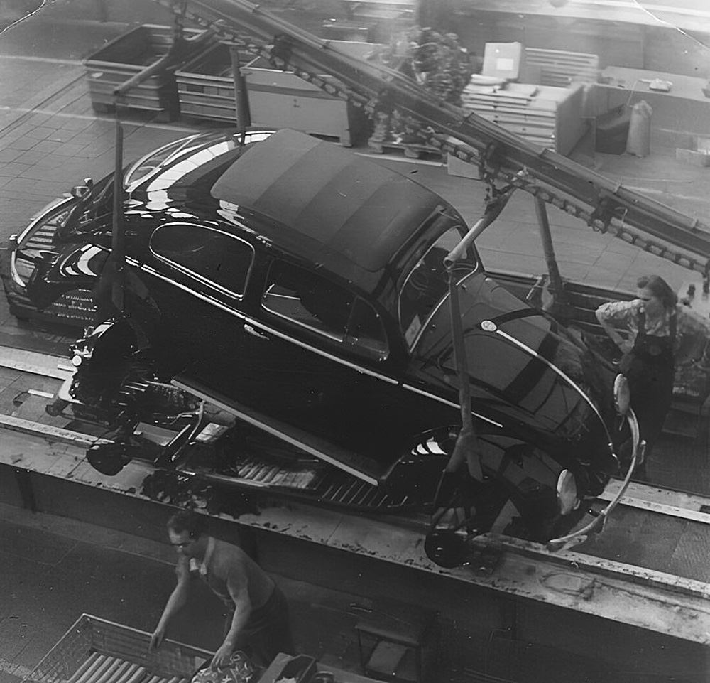 The completed body of an oval-window sunroof Beetle is carefully lowered onto its allocated chassis and running gear for the Hochzeit in the final assembly hall at Volkswagenwerk Wolfsburg