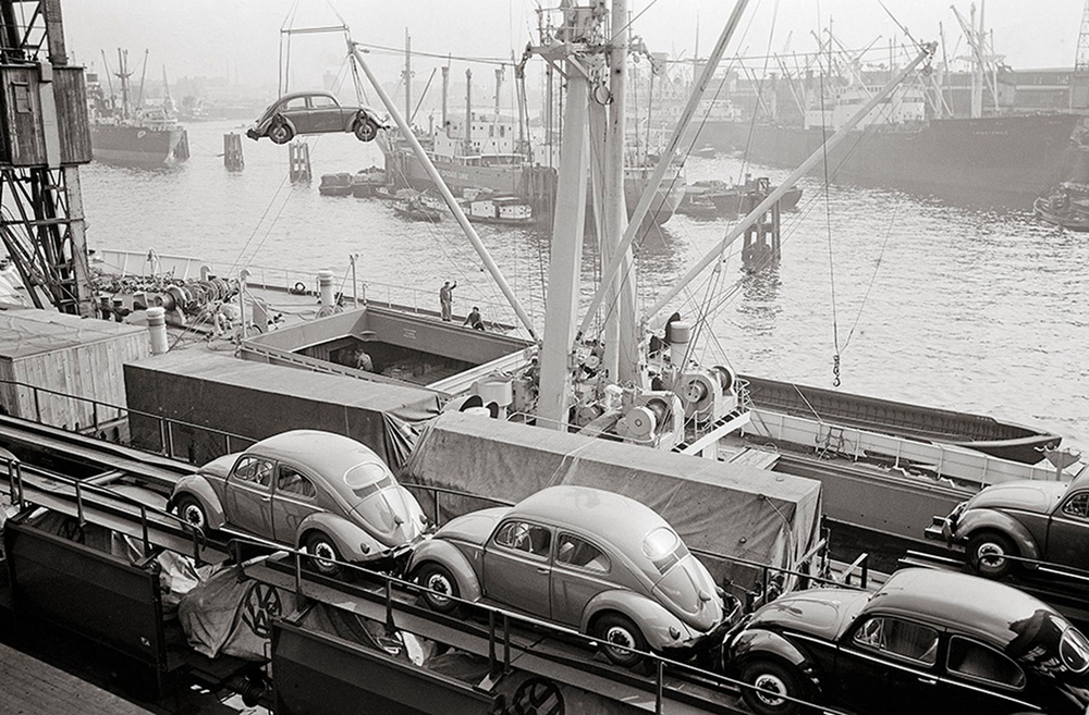 Beetles and Kabrioletts, with their distinctive covers, being loaded on to a ship at the port of Hamburg. The train ran directly to the docks.